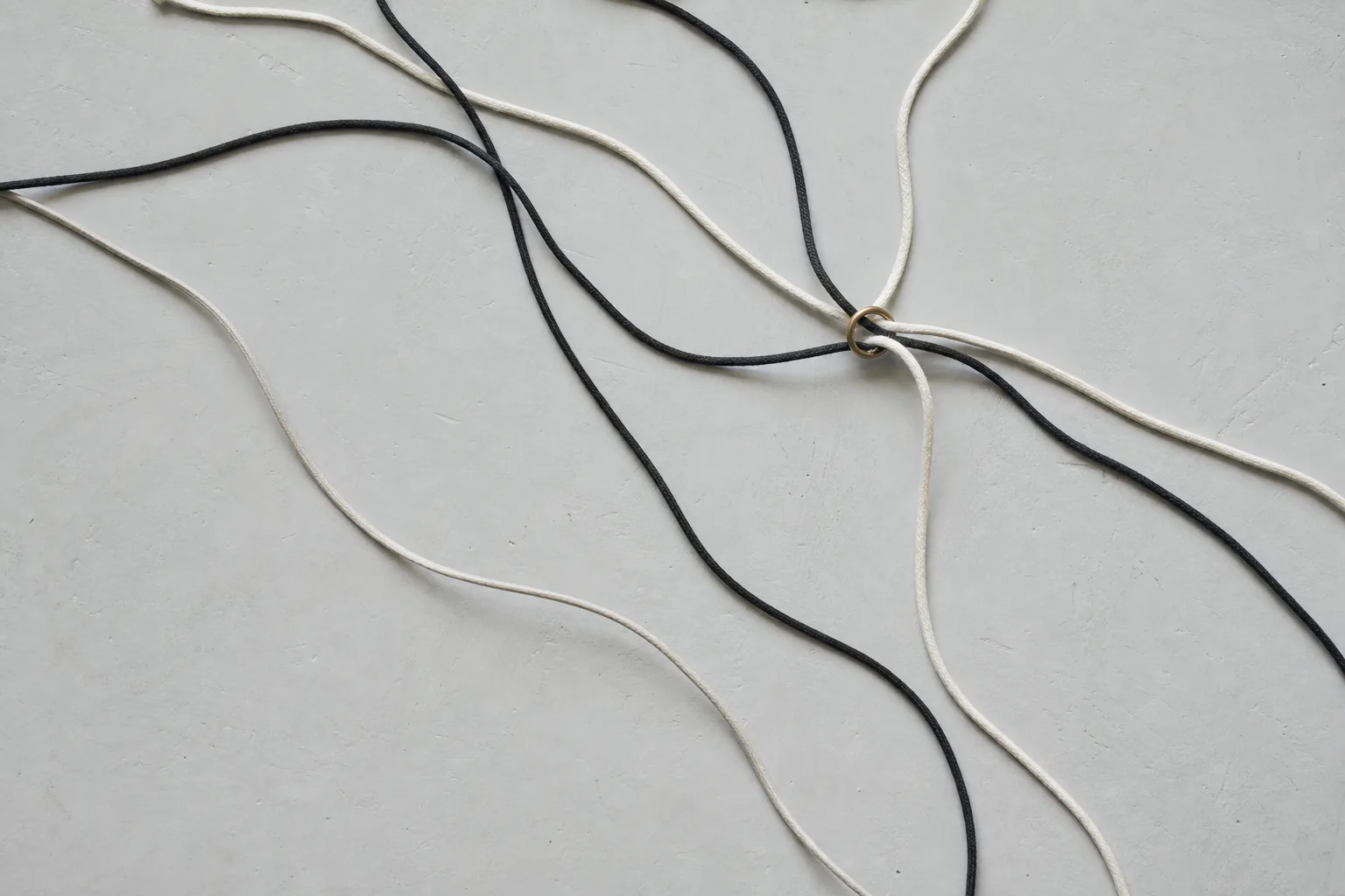 Black and cream cords passing through a small brass ring