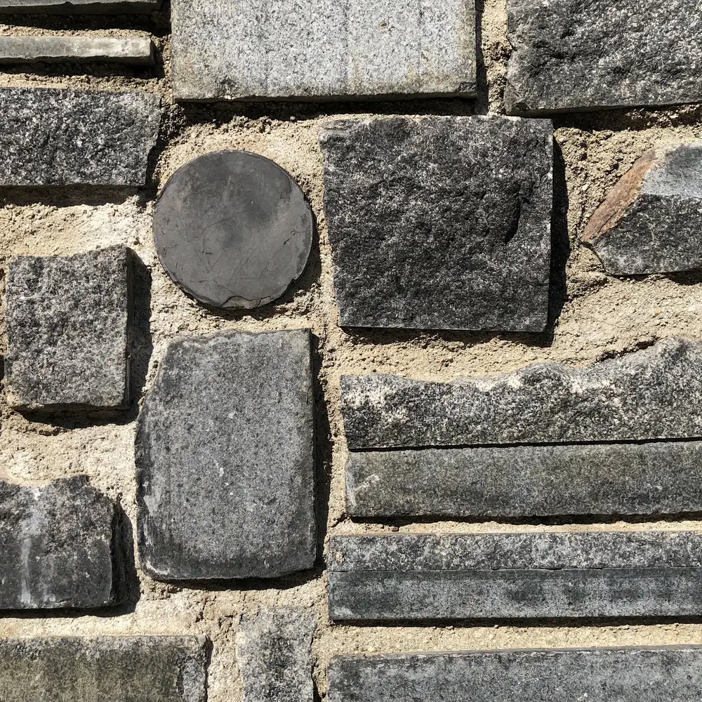 A grid of dark stones arranged in sand