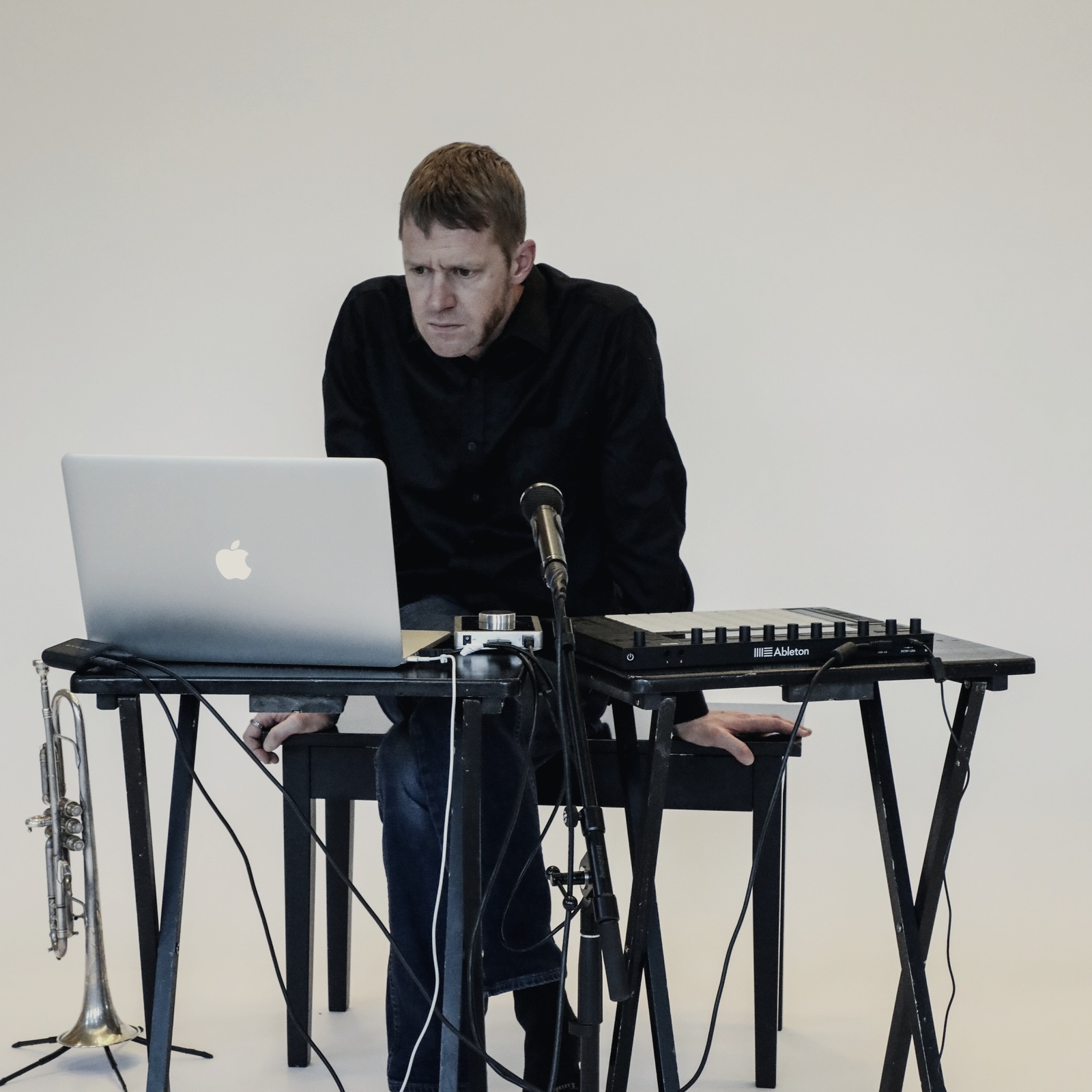 Michael Wall at a table with laptop, microphone, trumpet, and Ableton controller